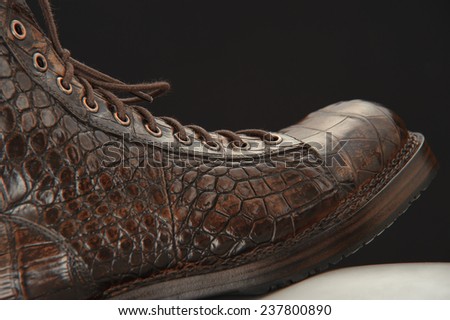 Brown leather patent leather shoes for men on a dark background.