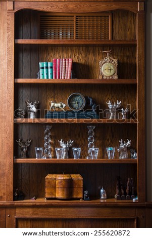 Wooden cabinet in the living room with the clock, glasses, books, candles and boxes.