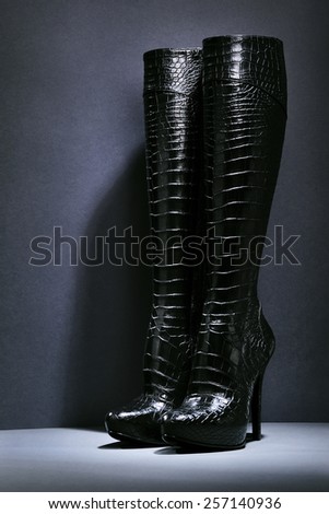 Black patent leather women\'s boots on a dark background