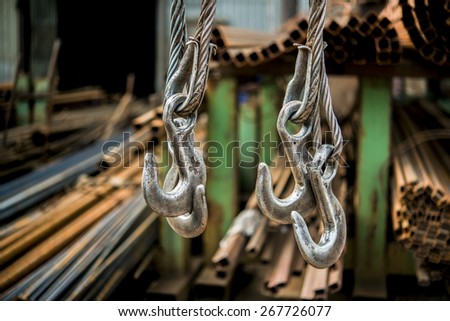 Steel hooks hang on the background of rolled metal products factory warehouse