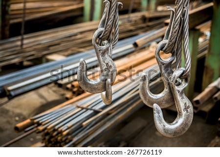 Steel hooks hang on the background of rolled metal products factory warehouse
