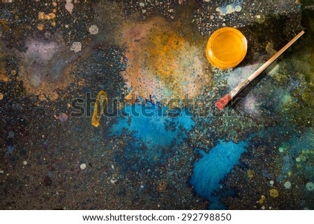 The artist\'s palette. Spray droplets and smears on a dark background. Nearby are open cans of paint and brushes.