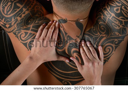 Woman doing massage a man on the back. On the back of a beautiful ethnic tattoo