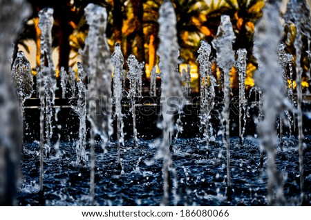 Water Fountain on an outdoor park with blue clear dripping water and blurred background