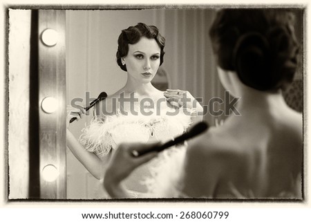 Beautiful  woman looking at herself in the mirror. Portrait in retro flapper style .  Old photo. Vintage toning.