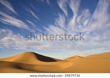 sand dunes with cloudy blue desert sky in the moroccan sahara