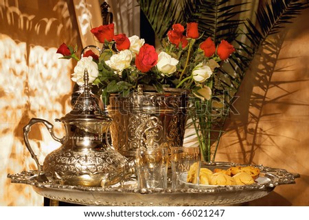 Moroccan tea set with pasteries and white and red roses. Traditional arabic and moroccan tea culture.