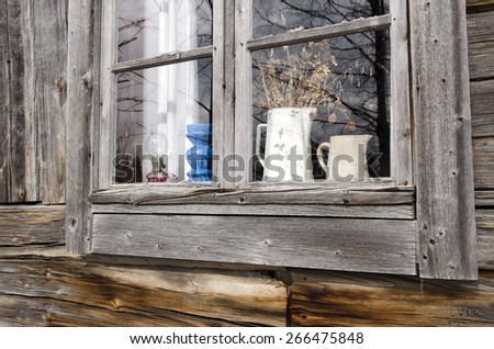 Window in a old timbered house with some summer flowers left on inside, photo taken in the North of Sweden