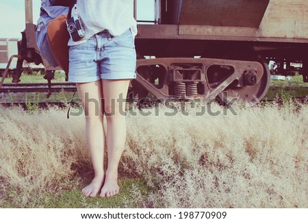 An Asian woman with  bag and film camera stands in front of an old train, vintage filter