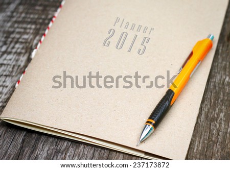 planner 2015 with a clutch-type pencil on an old wooden table for making plans of the year 2015