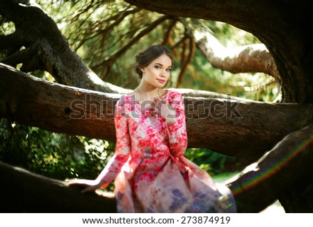 Gorgeous girl in colorful dress in magic garden