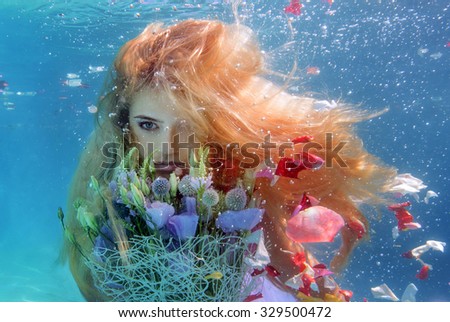 Unbelievable underwater beauty blond girl with bouquet with petals of roses fly off from it. Real shot.