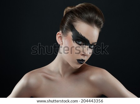 Black lightning on her beautiful face. Beautiful girl with full passionate black lips and stylish hair. Full dark make-up poses in studio on black background
