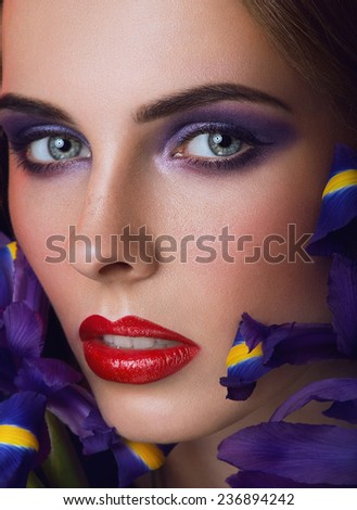 Close-up portrait of beauty young woman with purple eyeshadows and red lips with iris flowers