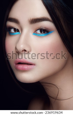 Close-up portrait of asian young girl with blue wings under hazel eyes and open lips with head to the left looking at you on black background