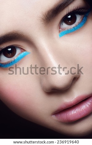 Facial portrait of asian young girl with blue wings under hazel eyes and open lips looking at you on black background