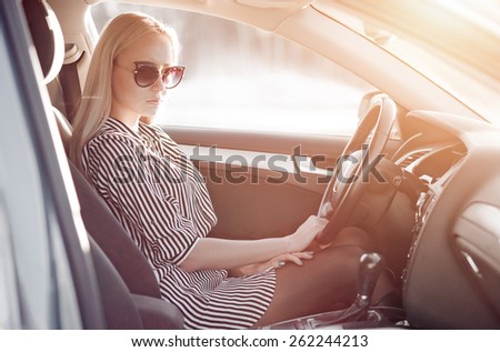 Beautiful portrait of blondie young lady at the wheel of sport car