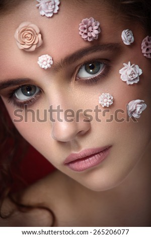 Romantic nude young beautiful girl with white flowers on her face and soft curls on dark background. Looking up. Beauty portrait. Creative make up. Dark background.Fashion.