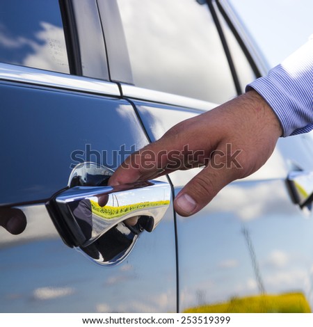 Businessman\'s hand opening door of his luxury car