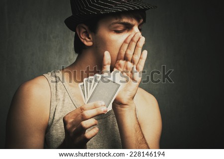 poker player whisper to someone holding cards in hand , studio shot