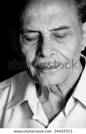 A portrait of a senior Asian man with his eyes closed. Monochrome.