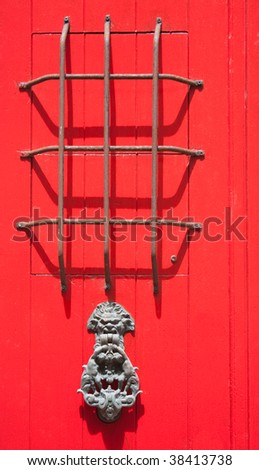 A bright red Spanish window grill with a door knocker