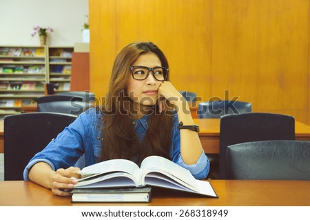 Portrait of asia student with open book reading it in university library