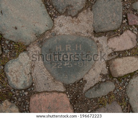 Pebble set in the ground on a path leading to the bridge crossing Watendlath Beck in the village of Watendlath, inscribed \