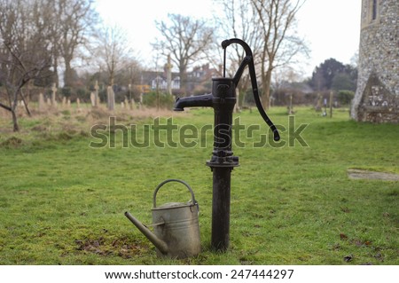 Hand Water Pump and Watering Can in the Churchyard of the Berkshire Village of Whitchurch Hill, England, UK