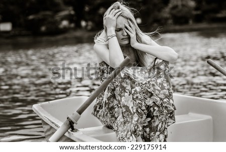Sad and depressed woman sitting alone on a rowboat