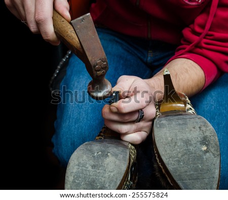 Young shoemaker repairing a old pair of shoes heel with a tool hamer