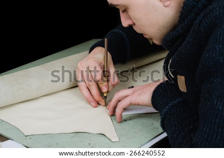 leather craftsman / shoemaker making a new lining for a wallet. Isolated on black background. Retro, nostalgic look