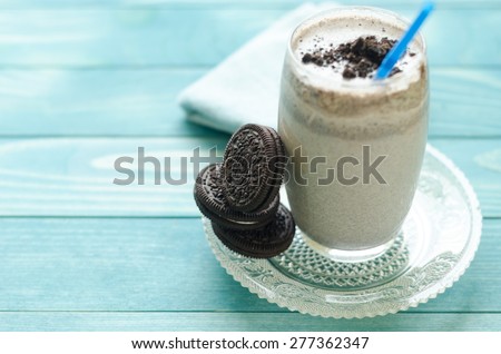 Milkshake (chocolate smoothie)  in a glass on colorful turquoise blue painted wooden boards.