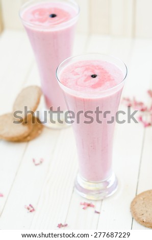 Pink Strawberry smoothie with brown cookies on light brown rustic table