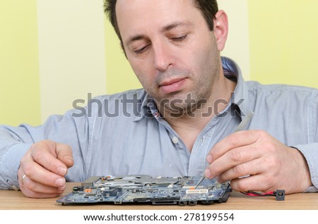 Computer engineer working on a broken motherboard at the office. Isolated on retro striped green and yellow wallpaper.