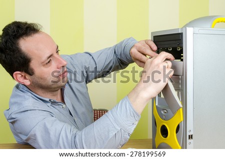 Computer engineer working on a broken computer at the office. Isolated on retro striped green and yellow wallpaper.