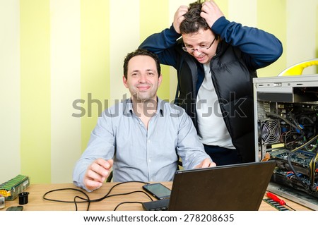 Happy computer engineer repairing broken computer while  male customer is looking despair with hands on his head and mouth open. Isolated on retro striped green and yellow wallpaper.