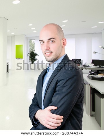 Portrait of good looking bald business man with crossed arm at the office