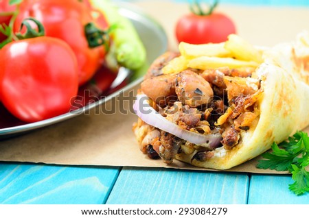 Traditional Greek pita gyros with meat, fried potatoes, tomato, onion and drink on brown Paper, Placed on blue Wooden Table board,
