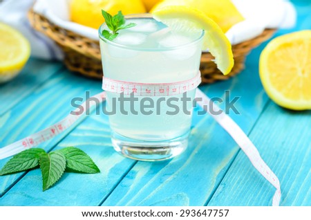 Cold glass of lemonade with ice, lemon and ginger on colourful turquoise blue painted wooden boards