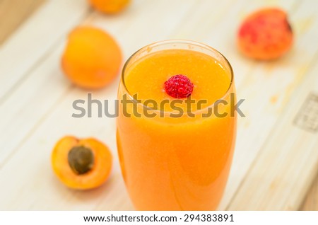 Glass of apricot and carrot juice on colourful turquoise blue pa