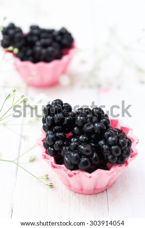 blackberry fruit in pink cup cake on a light wooden boards.