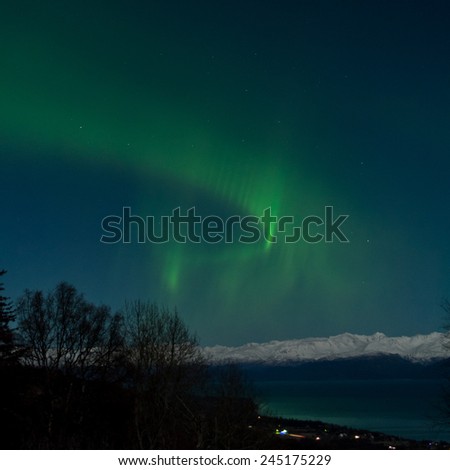 A green aurora forms a ribbon in the sky over Kachemak Bay Alaska.