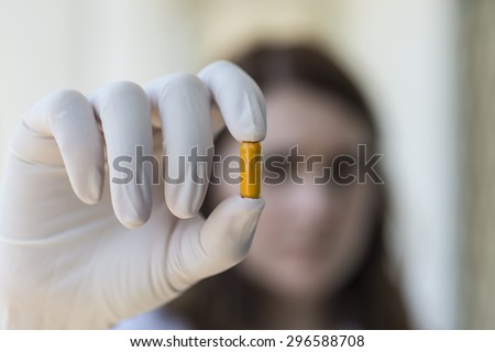 woman holding yellow pill capsules