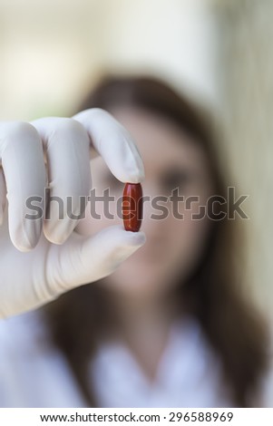 woman holding red pill capsules