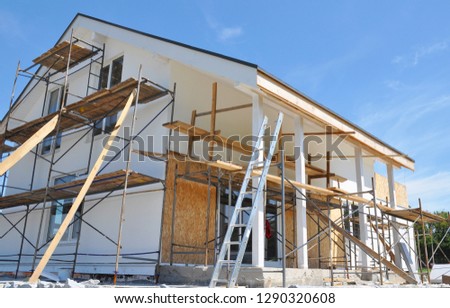 House renovation with wall insulation, plastering, paiting walls. House construction with scaffolding outdoor.