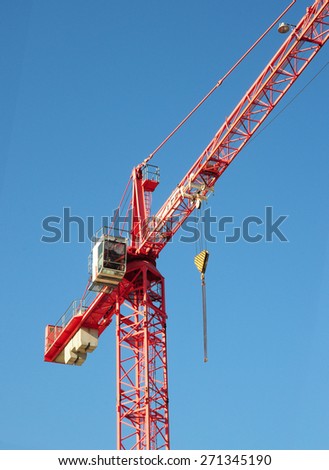 Red industrial construction crane above blue sky background