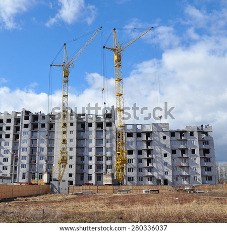 Building cranes and building under construction with people