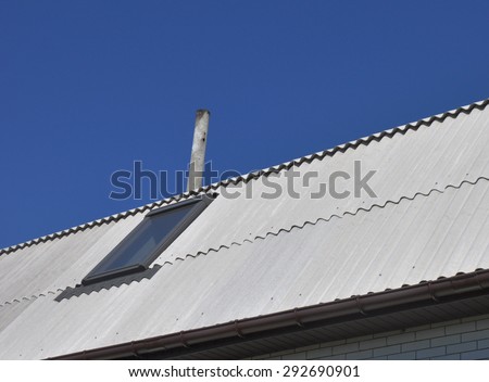 Use of asbestos in buildings is bad for health.\
Blue sky over the dangerous asbestos new roof tiles with roof window, skylights.