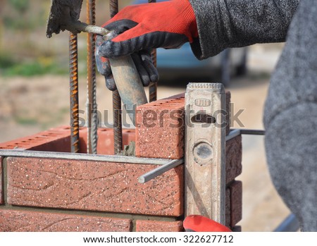 Bricklayer Worker Installing Red Clinker  Blocks and Caulking Brick Masonry Joints Exterior Wall with Trowel putty Knife  and Fixing with Spirit Level Outdoor